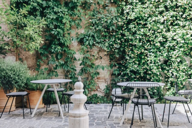 Vista del patio interior con una fuente, mobiliario y vegetación del hotel boutique Plácido y Grata en la ciudad de Sevilla.